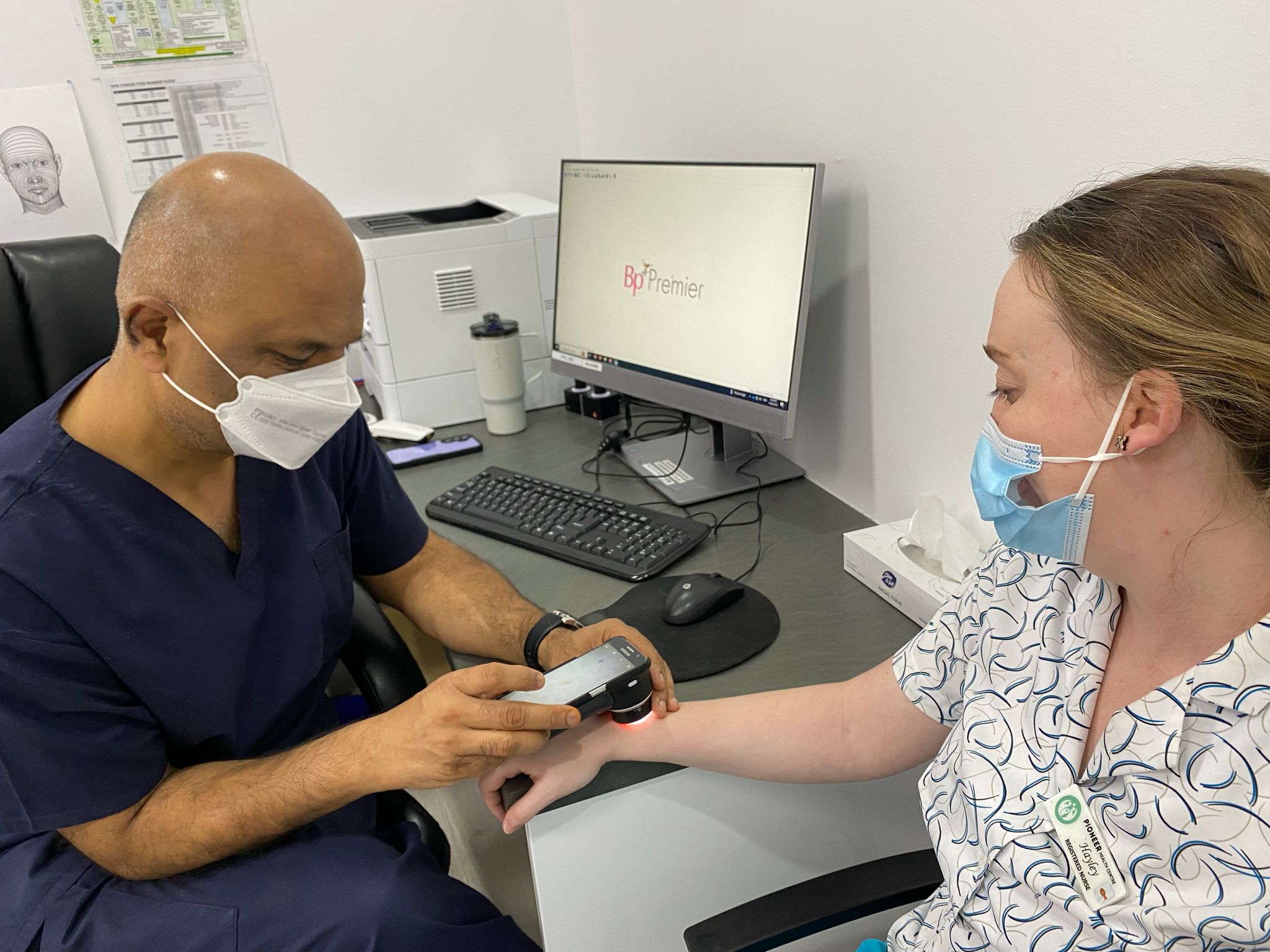 Doctor performing a dermoscopy skin examination on a patient's arm